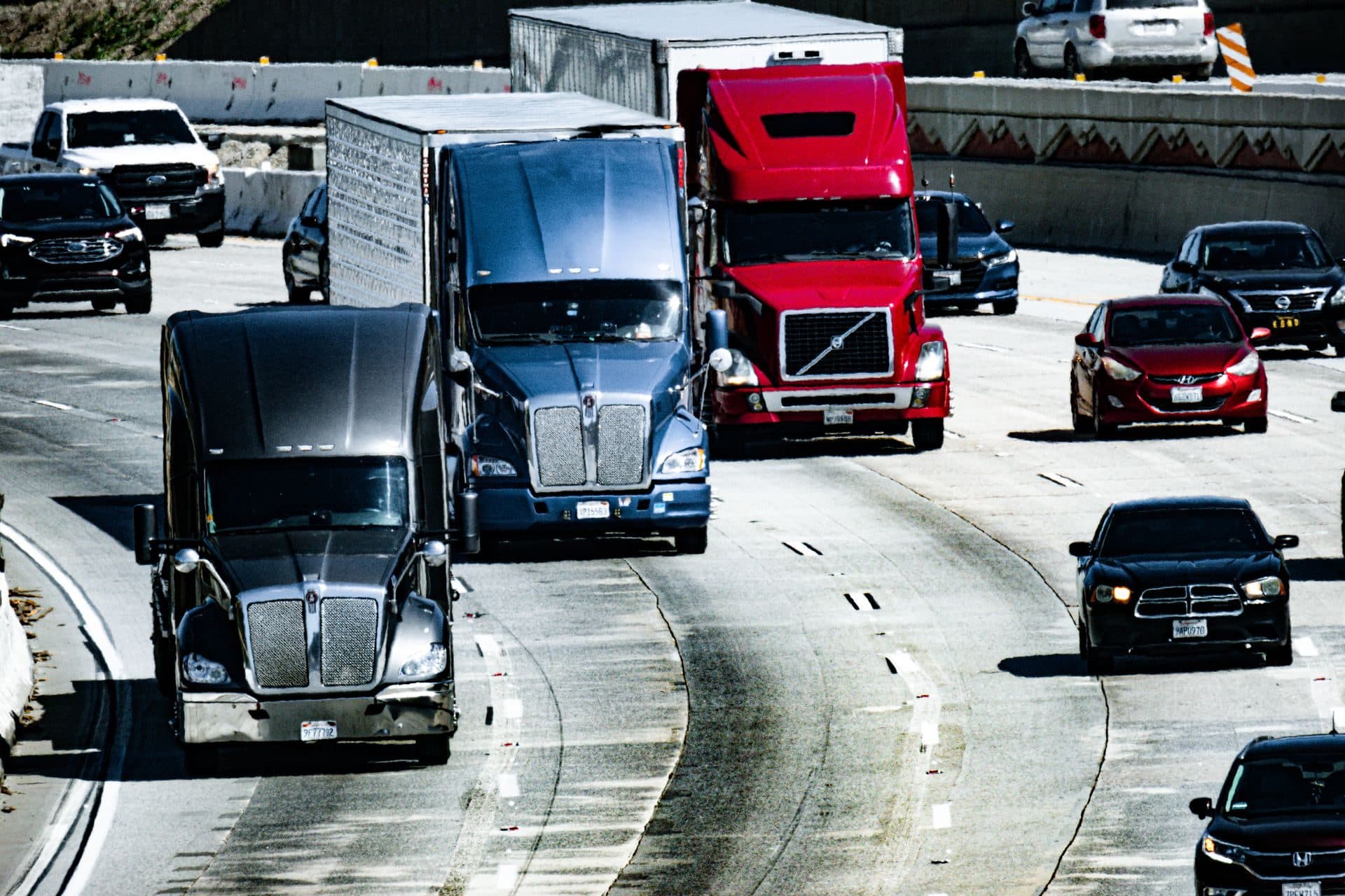 Three class 8 tractors in traffic on a California freeway, seen from an overpass